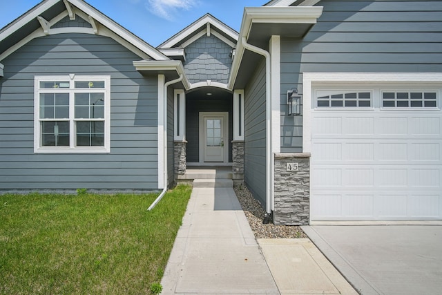 45 NW Alderleaf Dr, Waukee, IA 50263 - view of exterior entry with an attached garage, stone siding, a lawn, and concrete driveway