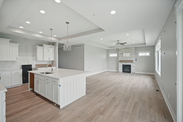45 NW Alderleaf Dr, Waukee, IA 50263 - kitchen with a tray ceiling, ceiling fan, light wood-style floors, a stone fireplace, and recessed lighting