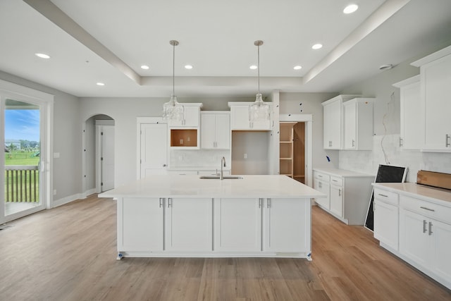 45 NW Alderleaf Dr, Waukee, IA 50263 - kitchen featuring tasteful backsplash, a center island with sink, arched walkways, light wood-style floors, and recessed lighting