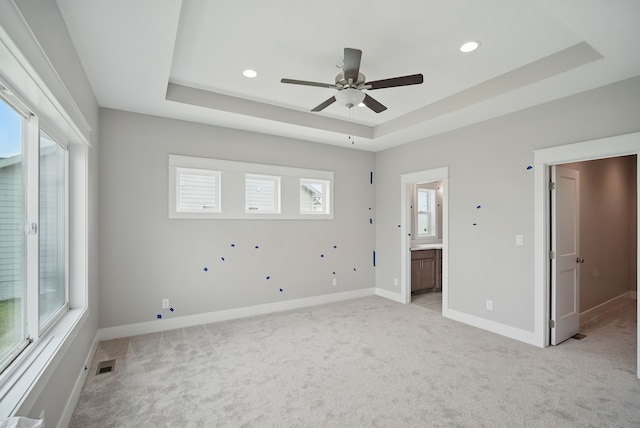 45 NW Alderleaf Dr, Waukee, IA 50263 - unfurnished bedroom with a raised ceiling, light carpet, multiple windows, recessed lighting, and ensuite bathroom