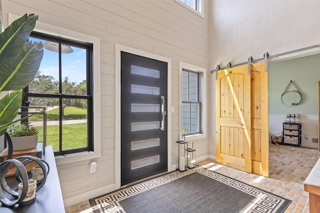 54 Four Winds Dr, Clear Lake, IA 50428 - entryway featuring a barn door, brick floors, wooden walls, and a high ceiling