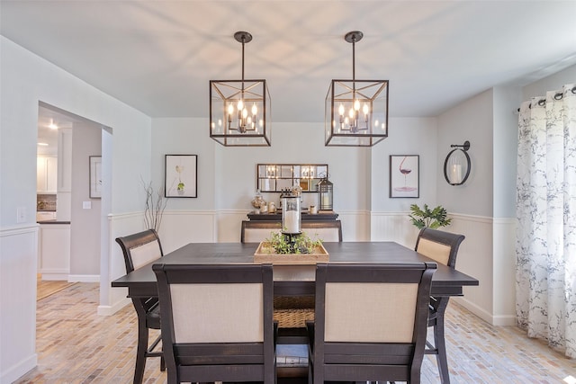 54 Four Winds Dr, Clear Lake, IA 50428 - dining room with a chandelier, brick floors, and wainscoting