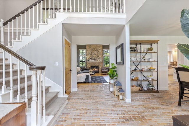 54 Four Winds Dr, Clear Lake, IA 50428 - foyer entrance with brick floors, stairway, a stone fireplace, and a high ceiling
