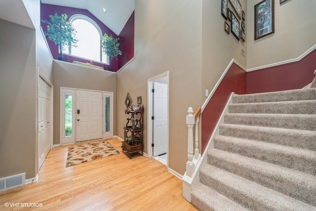 7100 Holcomb Ave, Urbandale, IA 50322 - entrance foyer featuring stairs, wood finished floors, high vaulted ceiling, and plenty of natural light