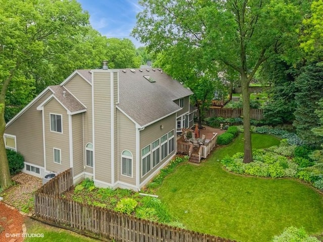 7100 Holcomb Ave, Urbandale, IA 50322 - rear view of house featuring a chimney, roof with shingles, a wooden deck, and view of wooded area