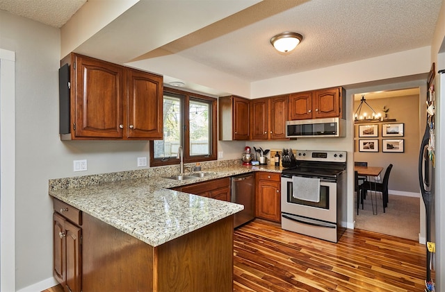 5208 Pommel Pl, West Des Moines, IA 50265 - kitchen featuring appliances with stainless steel finishes, a peninsula, a textured ceiling, a chandelier, and brown cabinetry