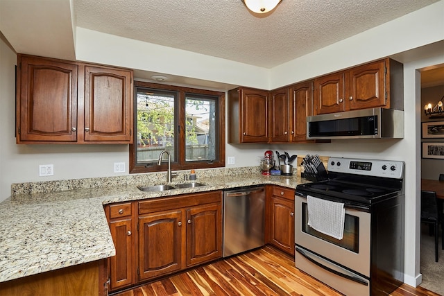 5208 Pommel Pl, West Des Moines, IA 50265 - kitchen with stainless steel appliances, wood finished floors, a textured ceiling, light stone counters, and brown cabinetry