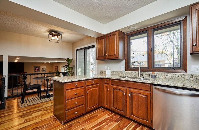 5208 Pommel Pl, West Des Moines, IA 50265 - kitchen with stainless steel dishwasher, a peninsula, light wood-style floors, a textured ceiling, and light stone counters