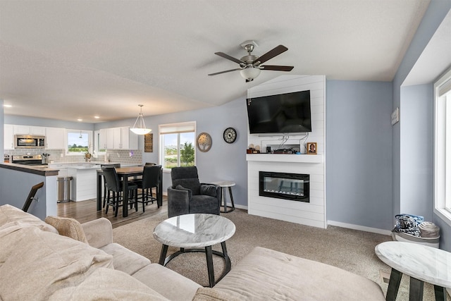 1115 Locust St, Waukee, IA 50263 - living area featuring a fireplace, a ceiling fan, light colored carpet, and vaulted ceiling