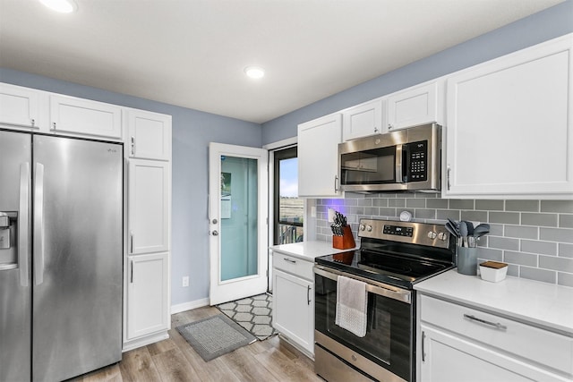 1115 Locust St, Waukee, IA 50263 - kitchen featuring stainless steel appliances, light countertops, white cabinetry, light wood-type flooring, and recessed lighting