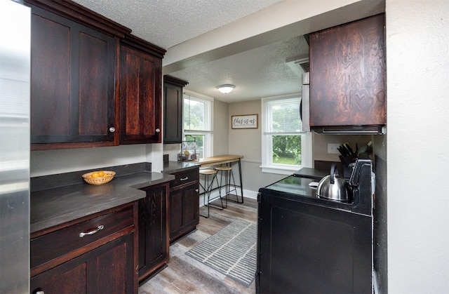 951 28th St, Des Moines, IA 50312 - kitchen featuring black electric range oven, light wood finished floors, dark countertops, and a textured ceiling