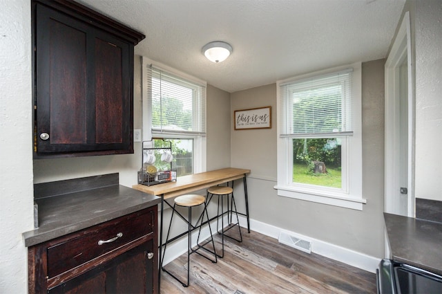 951 28th St, Des Moines, IA 50312 - kitchen with light wood-type flooring, dark brown cabinetry, and dark countertops