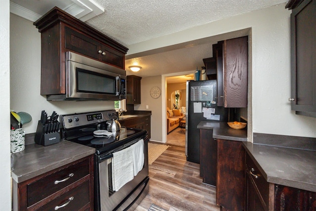 951 28th St, Des Moines, IA 50312 - kitchen with appliances with stainless steel finishes, light wood-type flooring, dark countertops, a textured ceiling, and dark brown cabinets