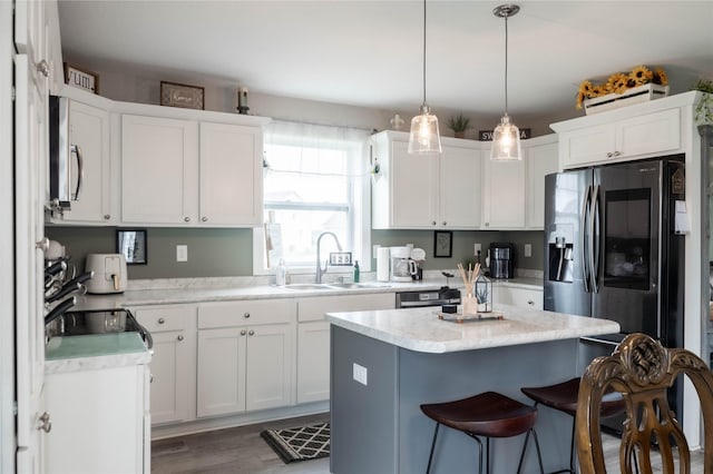 3635 Linden Dr SW, Bondurant, IA 50035 - kitchen with appliances with stainless steel finishes, a breakfast bar area, white cabinets, and a center island
