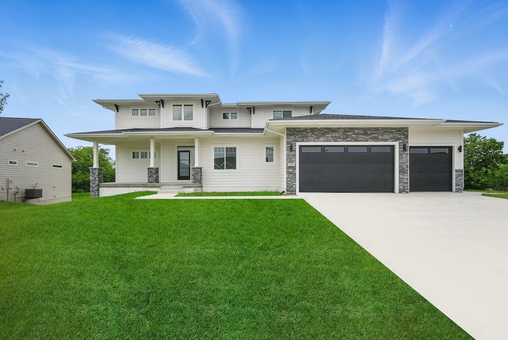 1310 NW Alderleaf Dr, Waukee, IA 50263 - view of front of home with an attached garage, a front lawn, concrete driveway, a porch, and stone siding