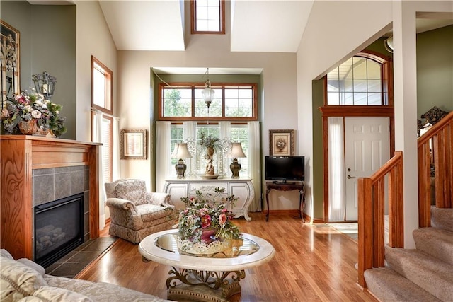 1699 Glade Dr SW, Altoona, IA 50009 - living area featuring high vaulted ceiling, stairway, a tile fireplace, and wood finished floors