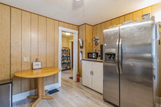 105 N St, Guthrie Center, IA 50115 - kitchen with stainless steel fridge, wooden walls, light wood-type flooring, and black microwave
