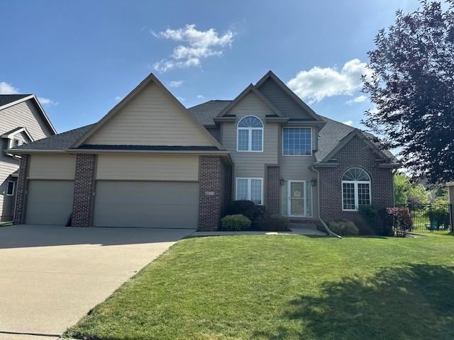 4017 160th St, Urbandale, IA 50323 - view of front of property featuring an attached garage, brick siding, concrete driveway, and a front yard