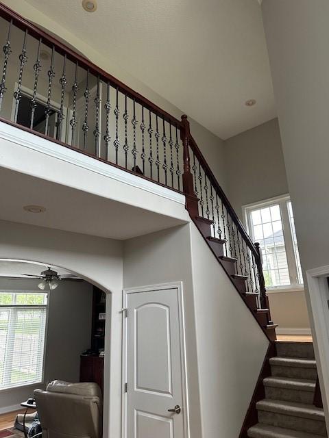 4017 160th St, Urbandale, IA 50323 - staircase featuring a high ceiling, ceiling fan, arched walkways, wood finished floors, and recessed lighting