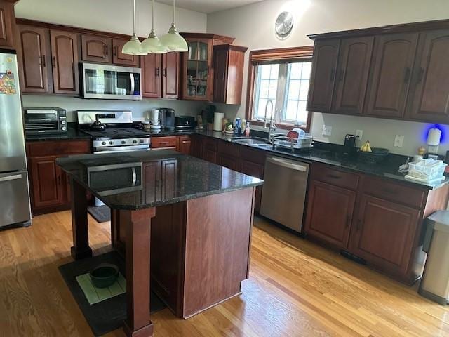4017 160th St, Urbandale, IA 50323 - kitchen featuring appliances with stainless steel finishes, light wood-type flooring, a center island, hanging light fixtures, and glass insert cabinets