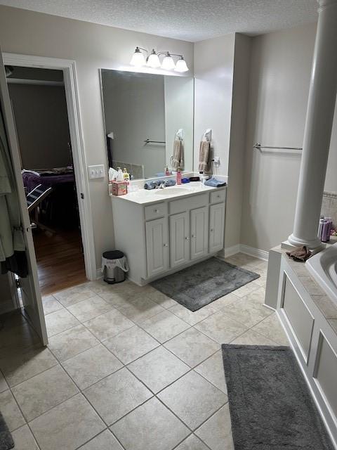 4017 160th St, Urbandale, IA 50323 - bathroom with decorative columns, vanity, tile patterned floors, a bath, and a textured ceiling