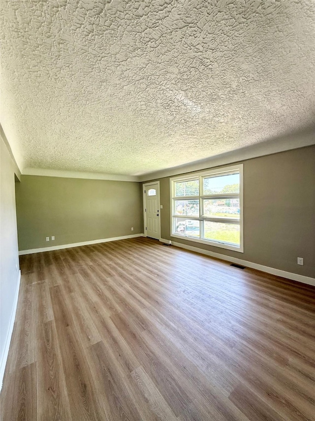 211 E Leach Ave, Des Moines, IA 50315 - unfurnished living room featuring a textured ceiling and wood finished floors
