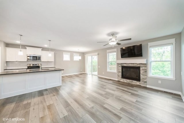 112 Hickory Way, Polk City, IA 50226 - unfurnished living room featuring light wood-type flooring, plenty of natural light, a ceiling fan, and a fireplace