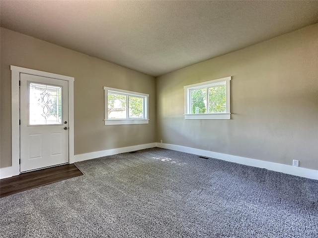 507 W Lincoln Way, Jefferson, IA 50129 - entrance foyer featuring dark carpet, plenty of natural light, and a textured ceiling