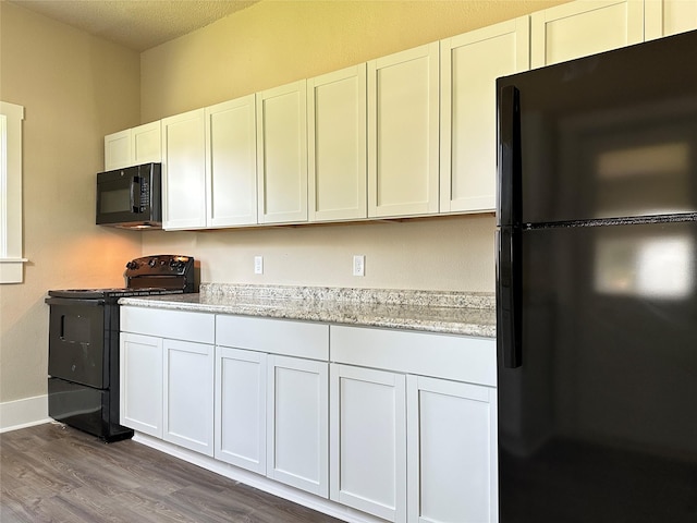 507 W Lincoln Way, Jefferson, IA 50129 - kitchen with black appliances, dark wood-style flooring, white cabinets, light stone countertops, and a textured ceiling