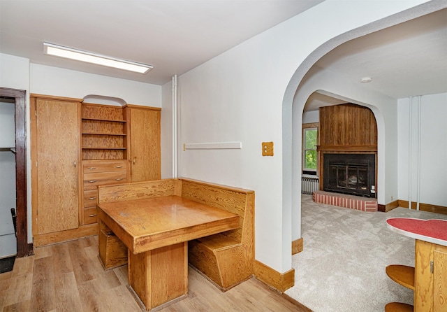 213 S Wilmoth Ave, Ames, IA 50014 - unfurnished dining area with arched walkways, light wood finished floors, radiator heating unit, and a glass covered fireplace