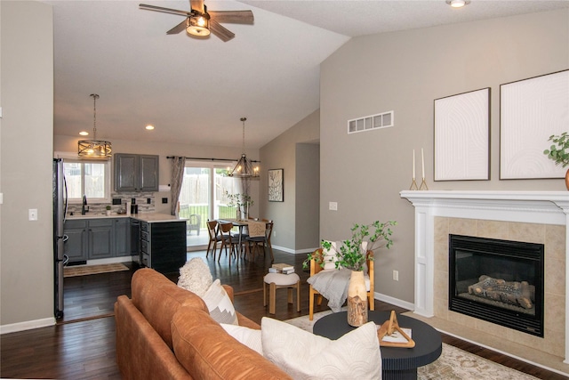 408 Tailfeather Ct NW, Bondurant, IA 50035 - living area featuring vaulted ceiling, a ceiling fan, dark wood-type flooring, a tiled fireplace, and recessed lighting