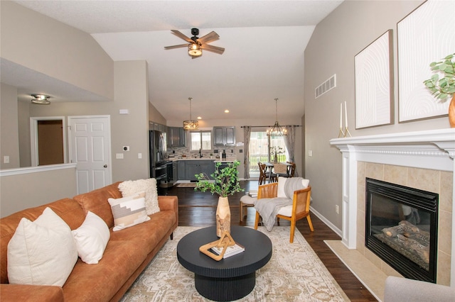 408 Tailfeather Ct NW, Bondurant, IA 50035 - living area featuring dark wood-style flooring, ceiling fan, a fireplace, high vaulted ceiling, and a chandelier