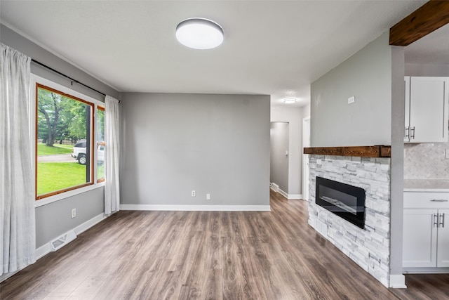 1115 E Herold Ave, Des Moines, IA 50315 - unfurnished living room with wood finished floors and a stone fireplace