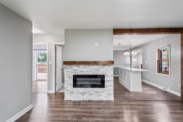 1115 E Herold Ave, Des Moines, IA 50315 - unfurnished living room featuring dark wood-type flooring, a stone fireplace, beamed ceiling, and a chandelier
