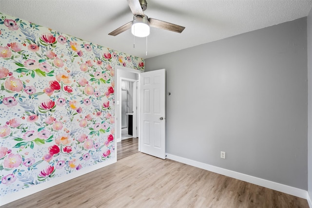 1115 E Herold Ave, Des Moines, IA 50315 - empty room with light wood-type flooring, ceiling fan, and wallpapered walls