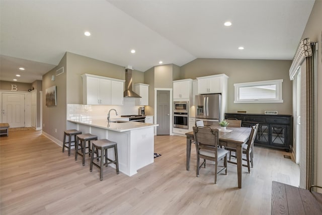 10214 Thorne Dr, West Des Moines, IA 50266 - kitchen featuring appliances with stainless steel finishes, wall chimney exhaust hood, a peninsula, a breakfast bar, and white cabinetry