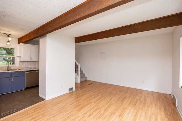1144 57th St, Des Moines, IA 50311 - unfurnished living room featuring stairway, beamed ceiling, wood finished floors, and a textured ceiling