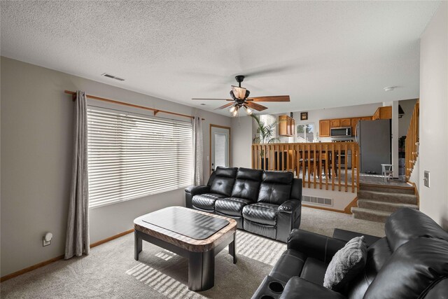 1215 7th Ave SE, Altoona, IA 50009 - living area with light carpet, healthy amount of natural light, a ceiling fan, and stairs