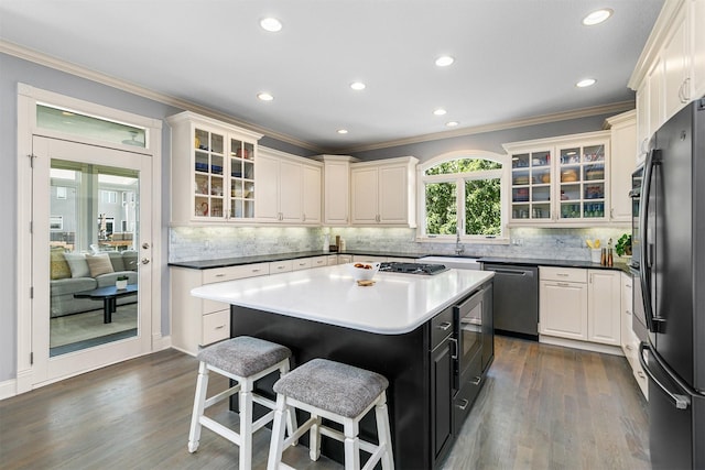 15222 Wilden Dr, Urbandale, IA 50323 - kitchen with stainless steel dishwasher, ornamental molding, freestanding refrigerator, a breakfast bar, and dark wood-type flooring