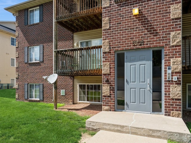 5908 Sutton Pl Unit 1, Urbandale, IA 50322 - doorway to property featuring a balcony, a yard, and brick siding