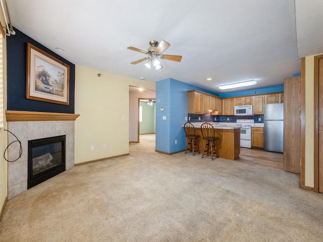 5908 Sutton Pl Unit 1, Urbandale, IA 50322 - kitchen with white appliances, a kitchen bar, a ceiling fan, a peninsula, and light colored carpet