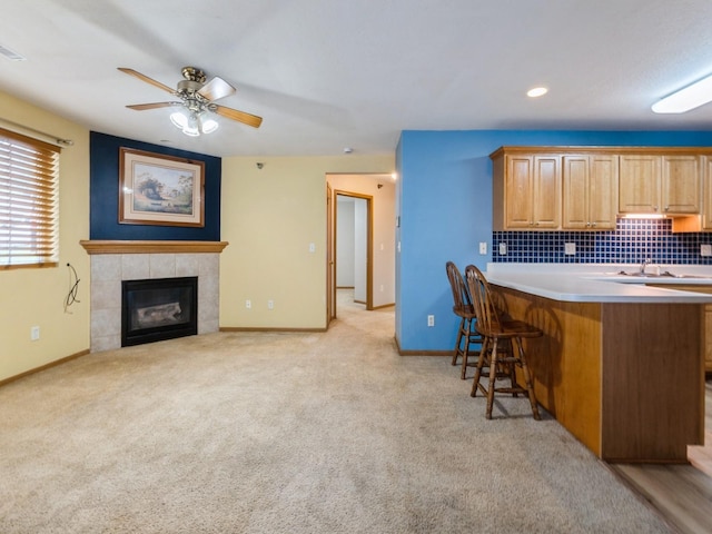 5908 Sutton Pl Unit 1, Urbandale, IA 50322 - kitchen featuring a breakfast bar, ceiling fan, light colored carpet, decorative backsplash, and a peninsula