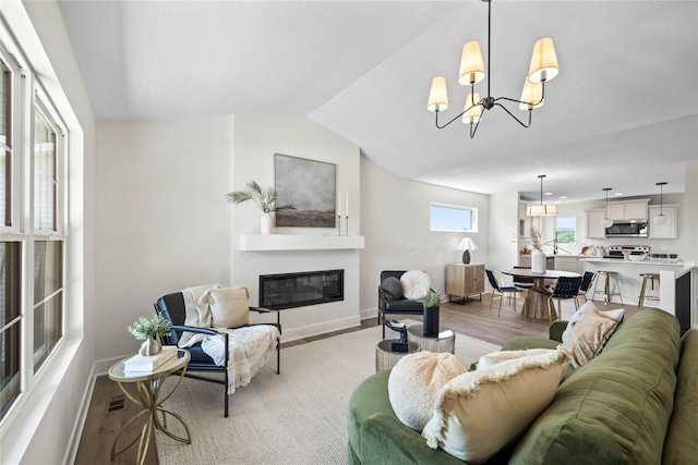 305 S Valley View Dr, Norwalk, IA 50211 - living room with light wood finished floors, a glass covered fireplace, a chandelier, and vaulted ceiling