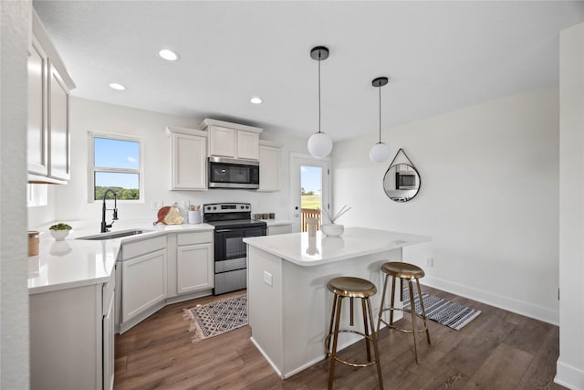 305 S Valley View Dr, Norwalk, IA 50211 - kitchen featuring stainless steel appliances, white cabinets, dark wood finished floors, a breakfast bar, and recessed lighting