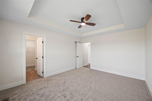 305 S Valley View Dr, Norwalk, IA 50211 - unfurnished bedroom featuring carpet floors, a tray ceiling, a spacious closet, a ceiling fan, and a closet