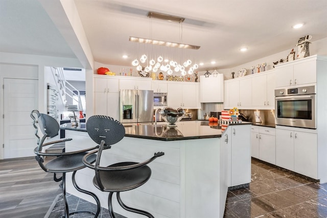 4709 Colt Dr, West Des Moines, IA 50265 - kitchen with appliances with stainless steel finishes, dark countertops, white cabinetry, a center island, and recessed lighting