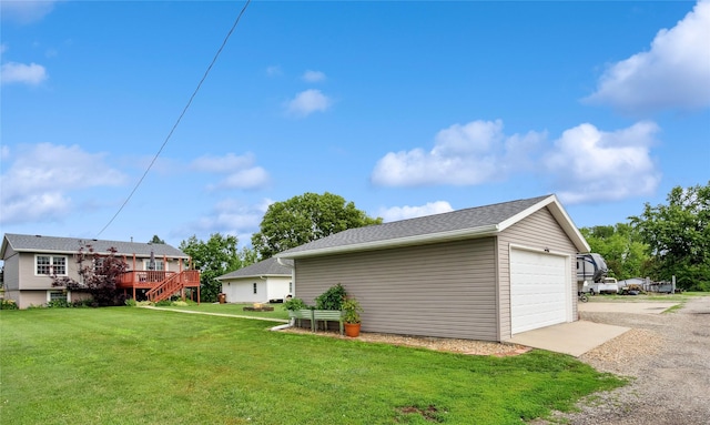 206 Main St, Grinnell, IA 50112 - view of green lawn featuring driveway, a deck, a detached garage, and an outbuilding