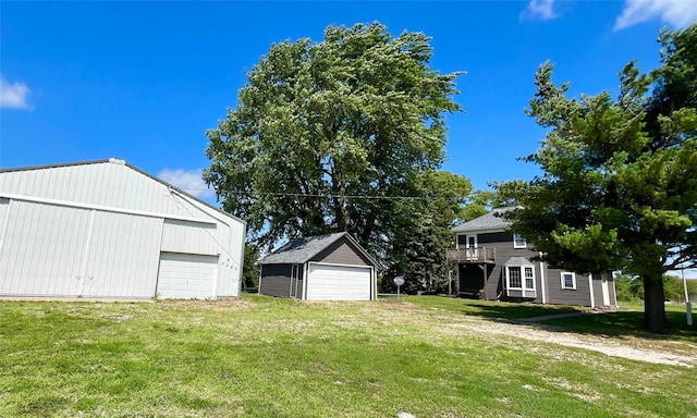 6285 E 28th St N, Newton, IA 50208 - view of grassy yard featuring a detached garage, an outdoor structure, and a deck