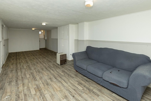 832 E Lacona Ave, Des Moines, IA 50315 - living room with light wood-style flooring, a textured ceiling, and a wainscoted wall