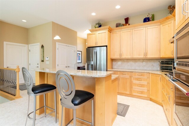 862 Glen Oaks Ter, West Des Moines, IA 50266 - kitchen with appliances with stainless steel finishes, light brown cabinetry, tasteful backsplash, a kitchen island, and a kitchen breakfast bar